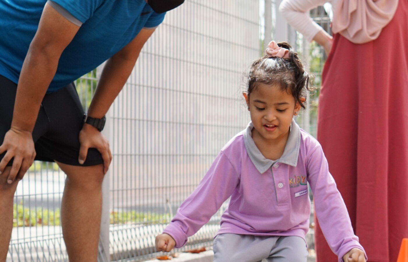 A child climbing outdoors with a teacher spotting