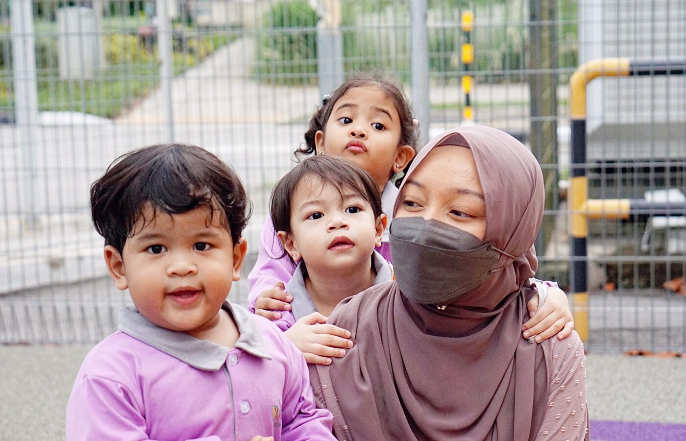 A teacher outdoors with two toddlers at Kidya Childcare