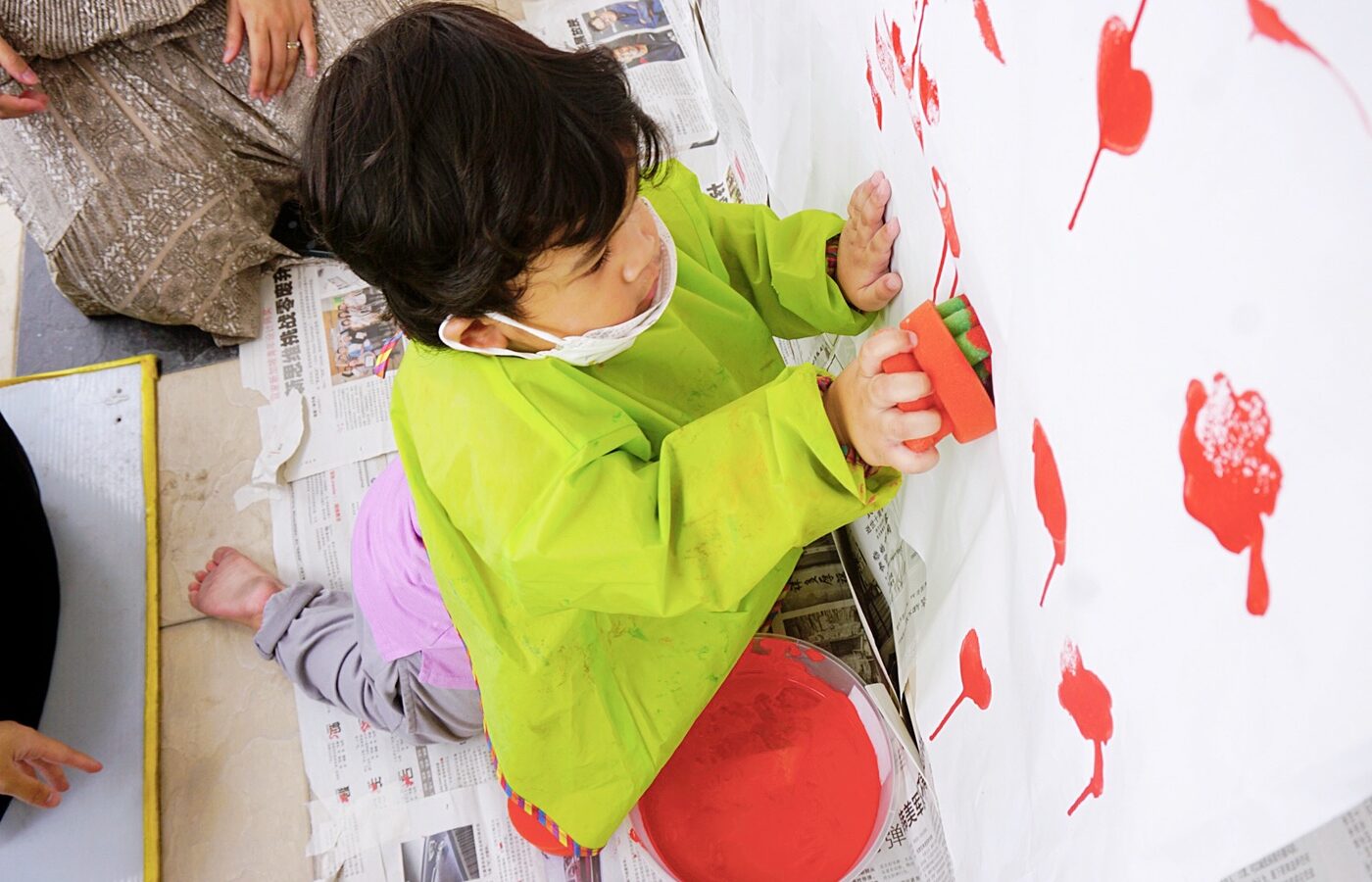 Children making red handprints on paper at Kidya Childcare