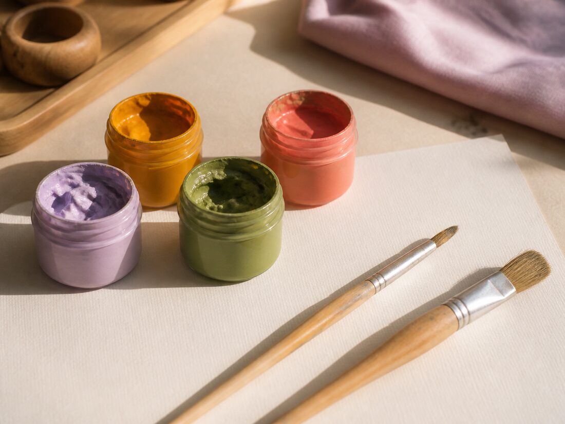 Pots of poster paint and brushes on paper