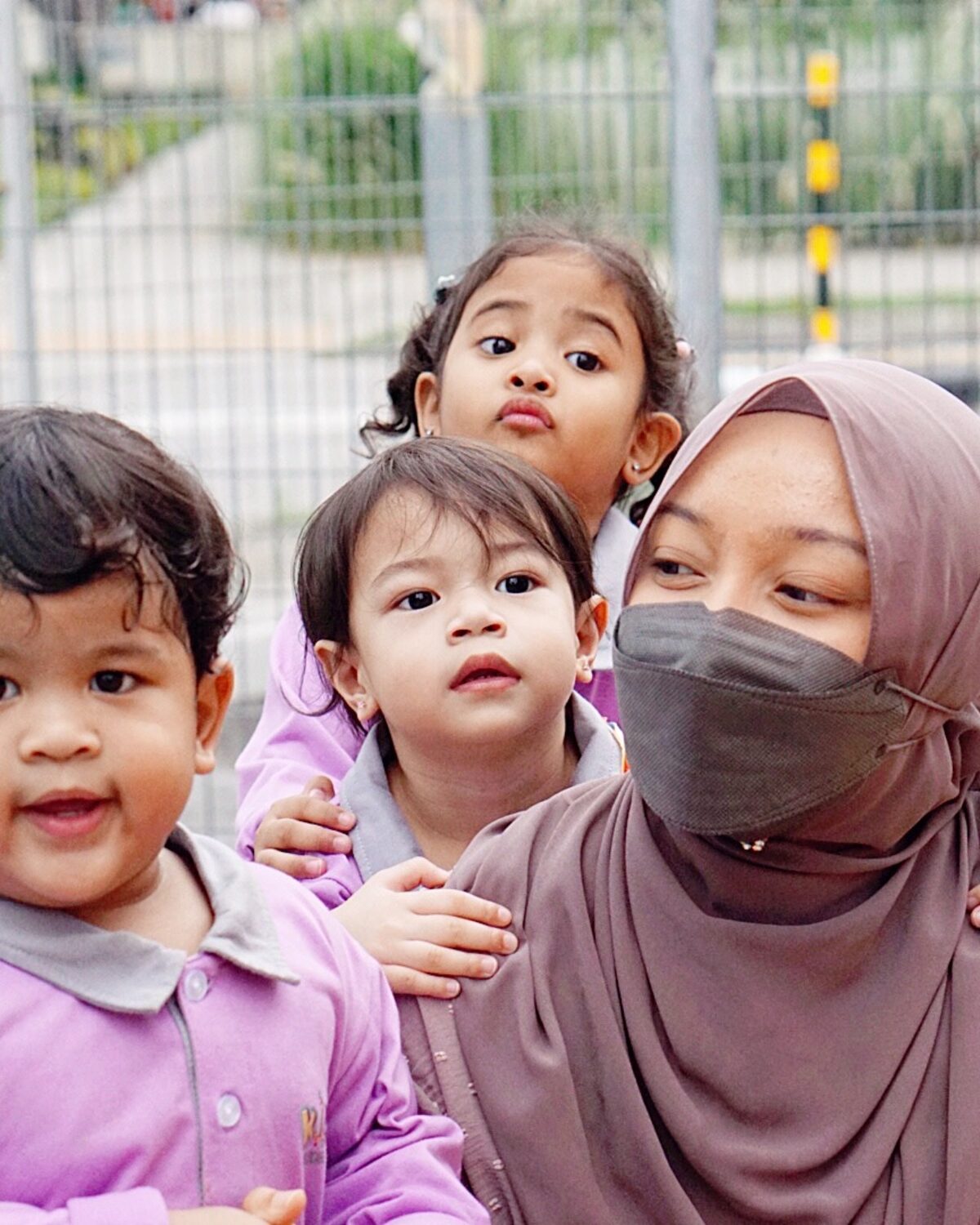 A Kidya teacher outdoors with two children